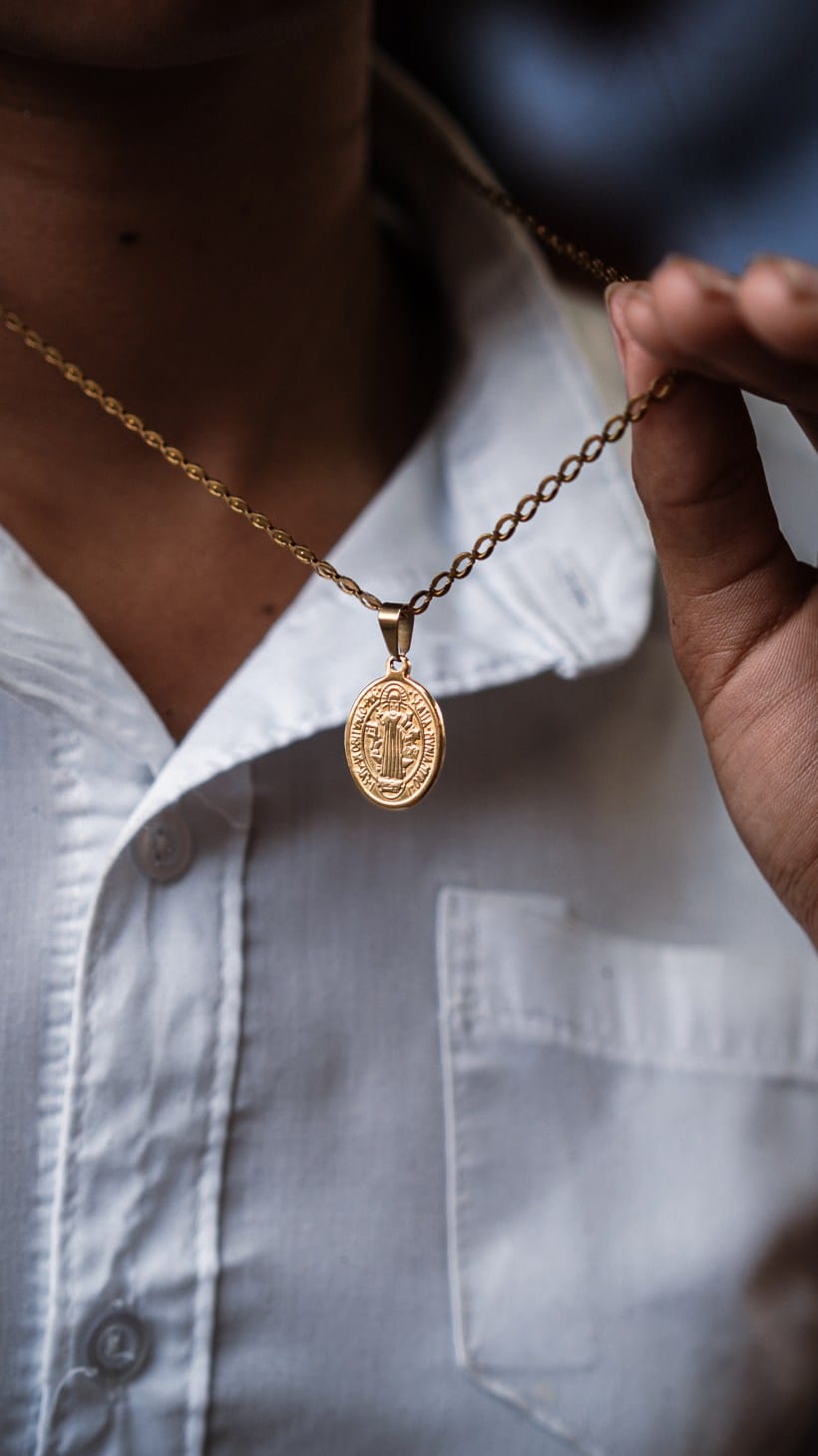 Sara de Perez's granddaughter, 16, holding the Saint Benedict medallion which her grandmother gifted to her; her father used to wear a similar one. [Euan Wallace/ Al Jazeera]